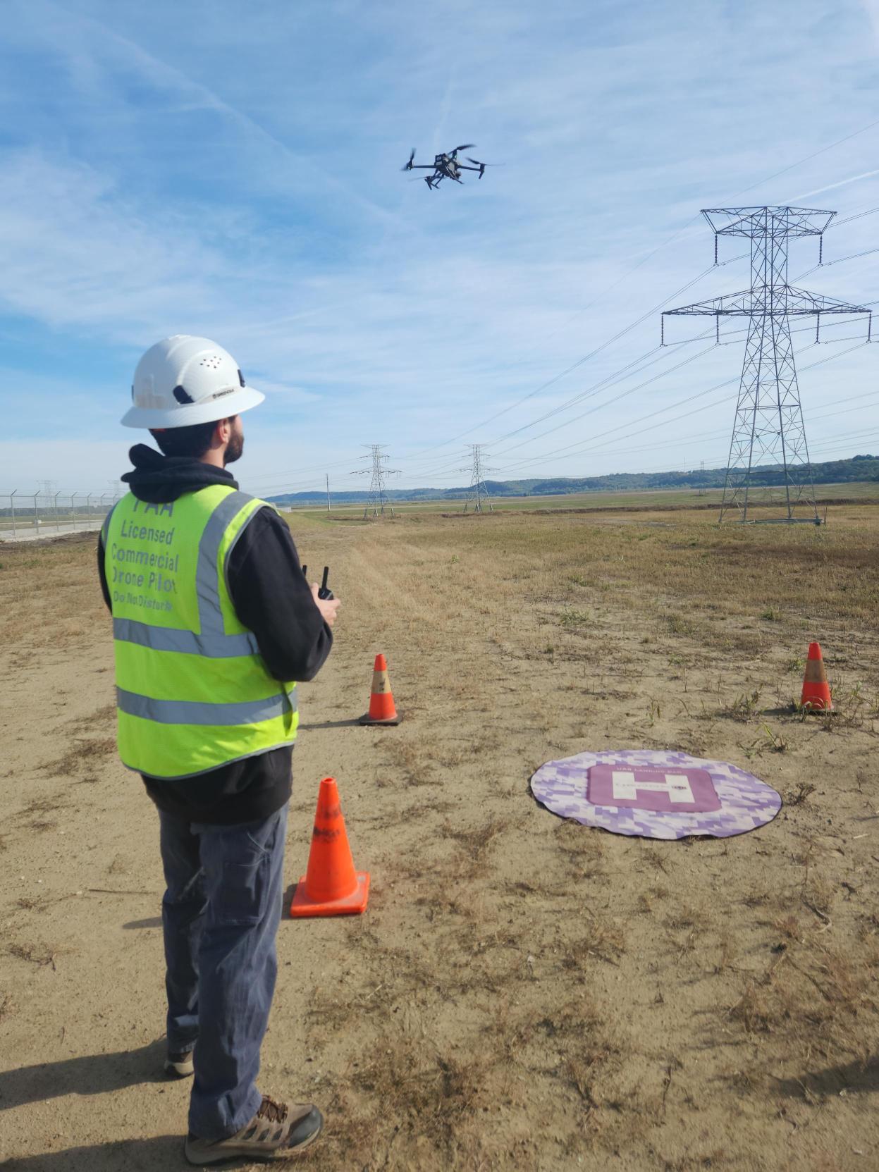 Drone operator landing a drone on a mat out in the field.